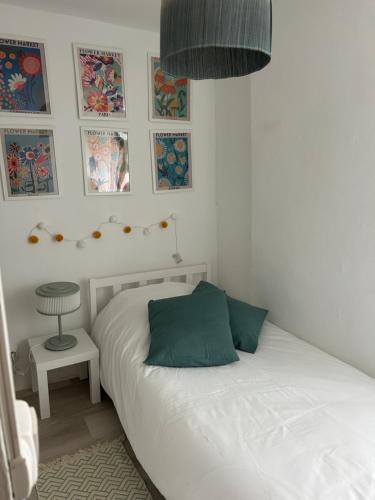 a bedroom with a white bed with a green pillow at La petite maison d'Arbas in Arbas