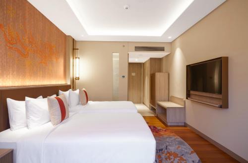 a hotel room with a large bed and a flat screen tv at Mason Pine Hotel Bandung in Padalarang