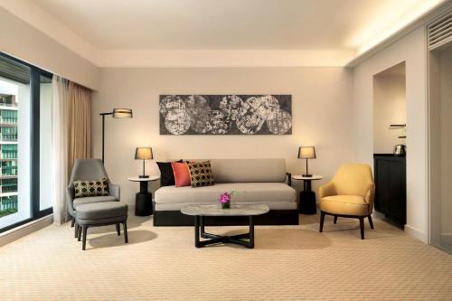 a living room with a couch and a table and chairs at Hilton Kuching Hotel in Kuching