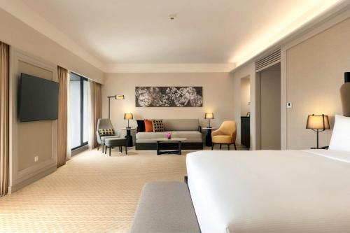a hotel room with a bed and a couch at Hilton Kuching Hotel in Kuching