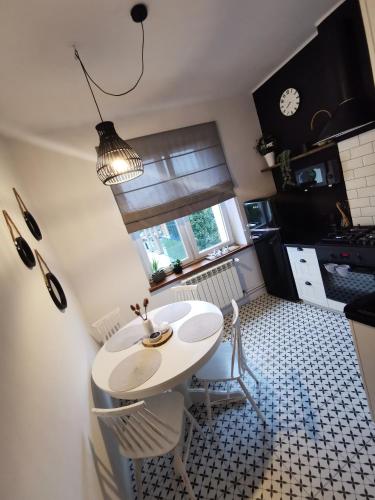 a kitchen with a white table and chairs and a window at Apartament Comfort Sanok in Sanok