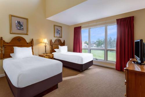 a hotel room with two beds and a window at Tamarack Wisconsin Dells, a Ramada by Wyndham in Wisconsin Dells