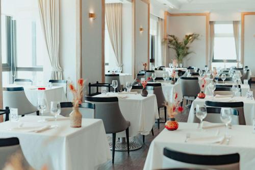 a dining room with tables and chairs with white table cloth at Radisson Montevideo Victoria Plaza Hotel in Montevideo
