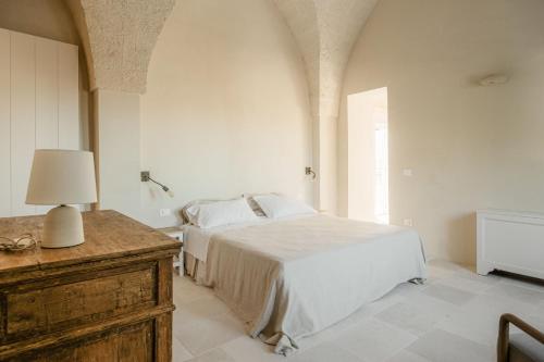 a bedroom with a bed and a table with a lamp at Masseria Vaccaro by Raro Villas - Self Check-in in Brindisi