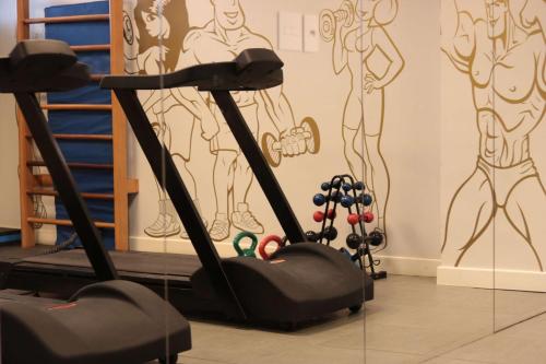 a gym with a treadmill and a wall with drawings at Hilton Garden Inn Maceio in Maceió