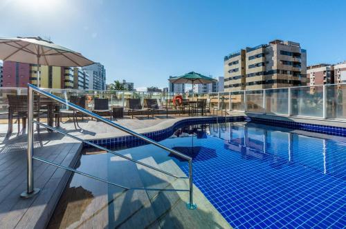 a swimming pool on top of a building with an umbrella at Hilton Garden Inn Maceio in Maceió