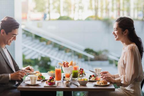 a man and woman sitting at a table eating food at Palace Hotel Omiya in Saitama