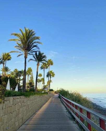 a boardwalk leading to the beach with palm trees at Ikos Andalusia in Estepona
