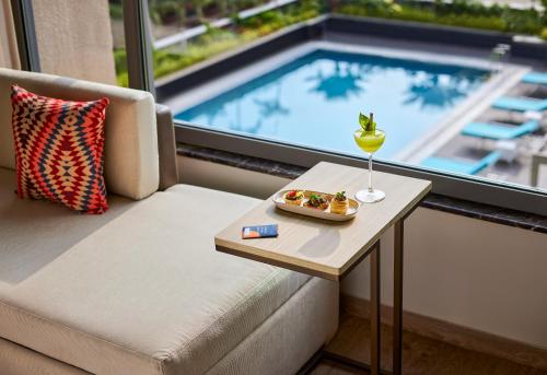 a room with a couch and a table with a drink at Hyatt Place Aurangabad Airport in Aurangabad