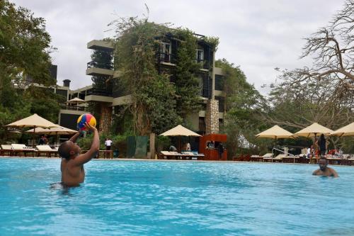 a boy playing with a beach ball in a swimming pool at Taita Hills Safari Resort & Spa in Tsavo