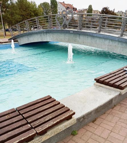 a bridge over a pool of water with a bench at Apartman Veki in Subotica