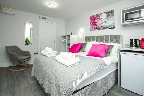 a bedroom with a large bed with pink pillows at Cosy Flamingo Studio in Sydenham in Forest Hill