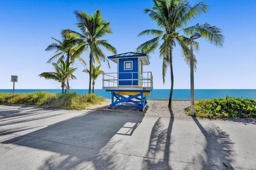 a blue life guard shack on a beach with palm trees at Waves On Desoto Rental Unit With Pool in Hollywood