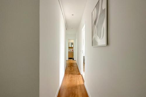 - un couloir dans une maison dotée de murs blancs et de parquet dans l'établissement Flexliving - room - Septembre, à Paris