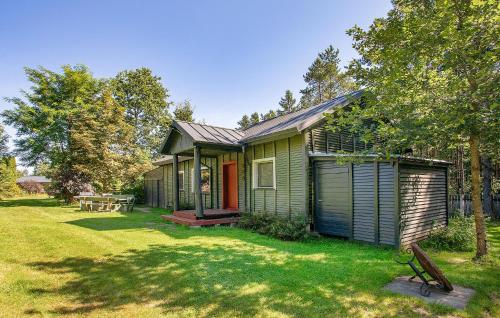 a green house with a red door in a yard at Nice Home In Poblocie With Sauna in Pobłocie