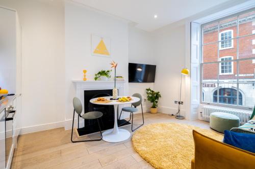 a living room with a table and chairs and a fireplace at Stay Kula London - Covent Garden Opera House in London
