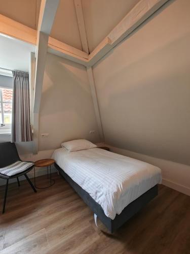 a small bedroom with a bed and a chair at Art Hotel Harlingen in Harlingen