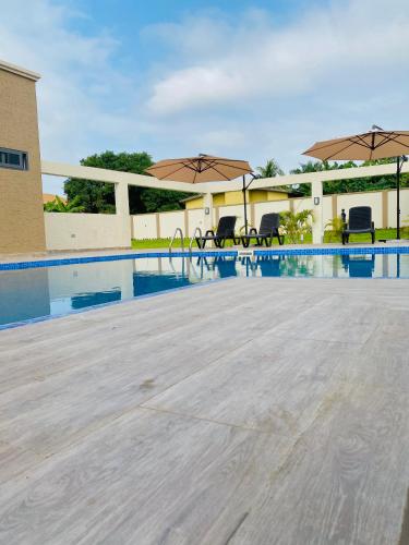 a swimming pool with chairs and umbrellas next to a building at AIDEN HOMES AND APARTMENTS HOTEl in Koforidua