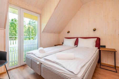 a large bed in a room with a large window at Namelis ant ežero kranto "Giliaus Elingas" in Tytuvėnai