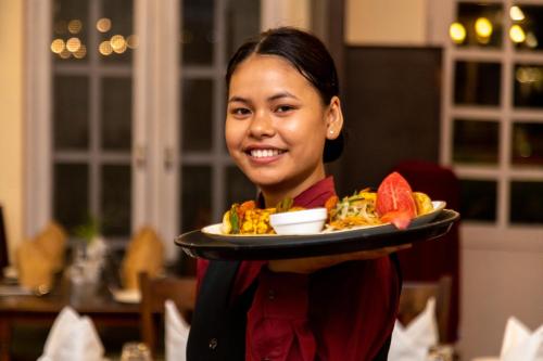 a woman is holding a plate of food at Dreamland Gold Resort & Hotel in Bhairāhawā