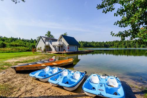 three boats on the shore of a lake with a house at Namelis ant ežero kranto "Giliaus Elingas" in Tytuvėnai