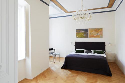 1 dormitorio con cama negra y lámpara de araña en Gut Purbach, en Purbach am Neusiedlersee