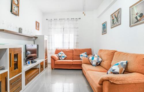 a living room with two orange couches and a tv at 2 Bedroom Amazing Apartment In Chipiona in Chipiona