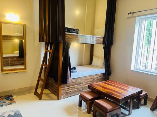 a room with a bunk bed with a bench and a table at Rootz in Dehradun