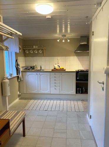 a kitchen with white cabinets and a tile floor at Björnamåla stuga in Asarum