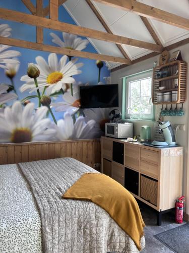 a bedroom with a bed and a wall with flowers at Bed en Brochje De Oase in Sweagerbosk 