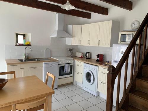 une cuisine avec lave-linge, sèche-linge et une table dans l'établissement Lake Cottage, In A Small Village, à Caurel