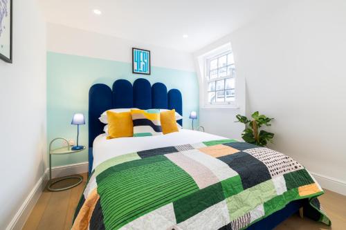 a bedroom with a blue and green bed with yellow pillows at Stay Kula London - Covent Garden Opera House in London