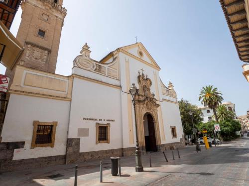 a white building with a clock tower on a street at Bhost - Palacete del Águila in Córdoba