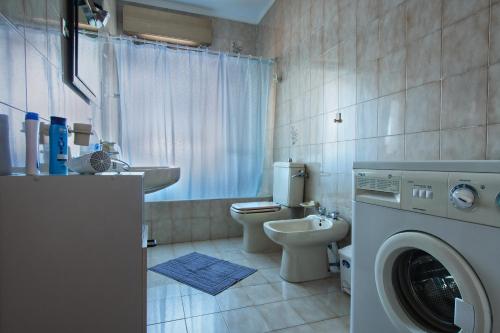 a bathroom with a toilet sink and a washing machine at Joanne B&B in Canicattini Bagni