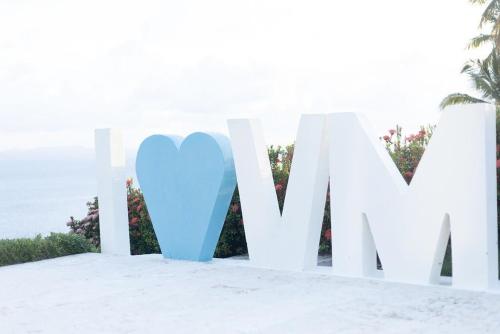 a white sign with a blue heart in the sand at Saman - Paradise With A View - Vista Mare in Santa Bárbara de Samaná