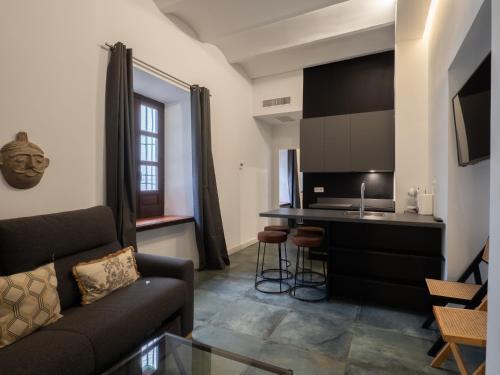 a living room with a couch and a kitchen at Bhost - Palacete del Águila in Córdoba