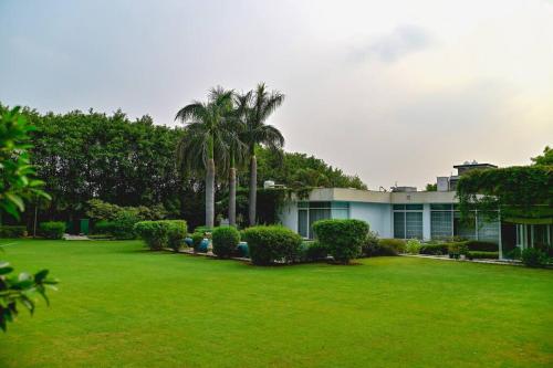 a green yard with palm trees and a building at Udman Luxe Villa Chattarpur in New Delhi