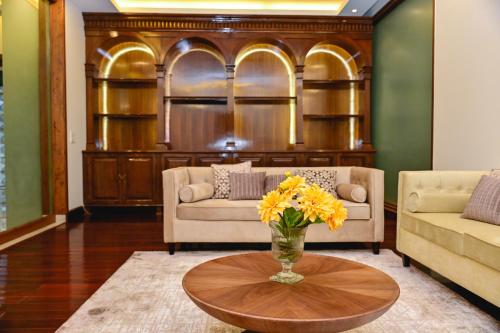 a living room with two couches and a table with yellow flowers at Udman Luxe Villa Chattarpur in New Delhi