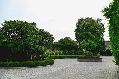 a courtyard with trees and bushes and a building at Udman Luxe Villa Chattarpur in New Delhi