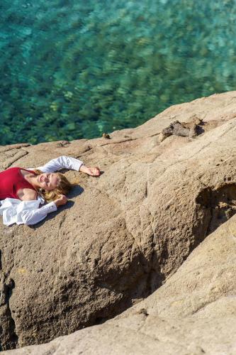 a young girl laying on a rock near the water at Ikos Aria in Kefalos