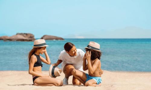 a group of three people sitting on the beach at Ikos Aria in Kefalos