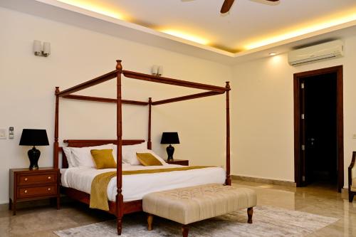 a bedroom with a four poster bed and a nightstand at Udman Luxe Villa Chattarpur in New Delhi