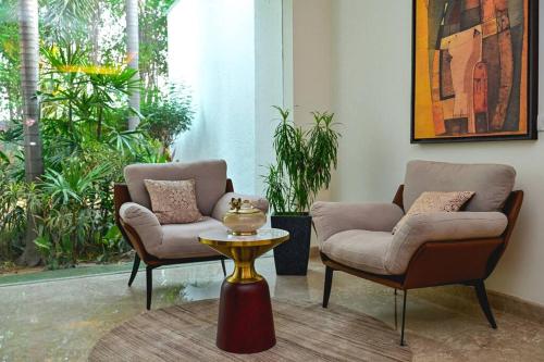 two chairs and a table in a room with plants at Udman Luxe Villa Chattarpur in New Delhi