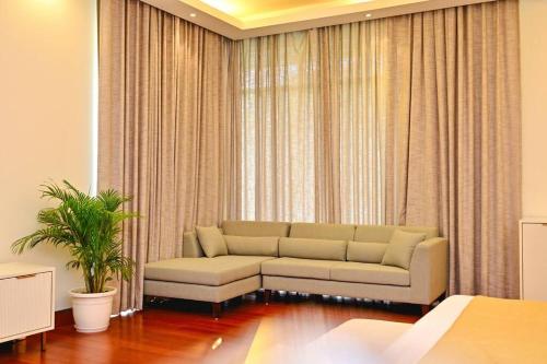 a living room with a couch in front of a window at Udman Luxe Villa Chattarpur in New Delhi