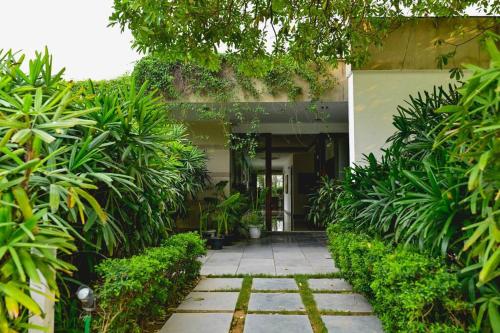 a walkway in front of a building with plants at Udman Luxe Villa Chattarpur in New Delhi