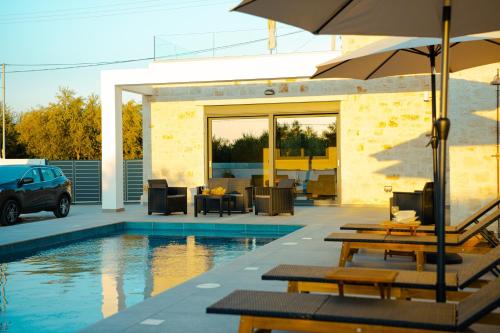 una piscina con mesas y sillas y una sombrilla en Seaside Villa Volter, en Kypseli