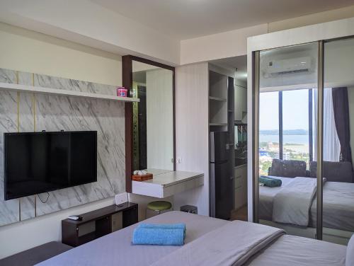 ein Hotelzimmer mit einem TV und einem Schlafzimmer in der Unterkunft SleepRest @ Pollux Habibie in Batam Center