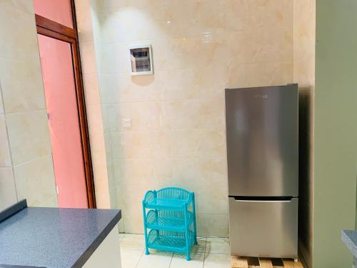 a stainless steel refrigerator in a kitchen with a blue chair at ROBERT Villa APARTMENT in Kigali