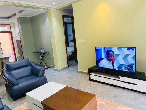 a living room with a flat screen tv and a couch at ROBERT Villa APARTMENT in Kigali