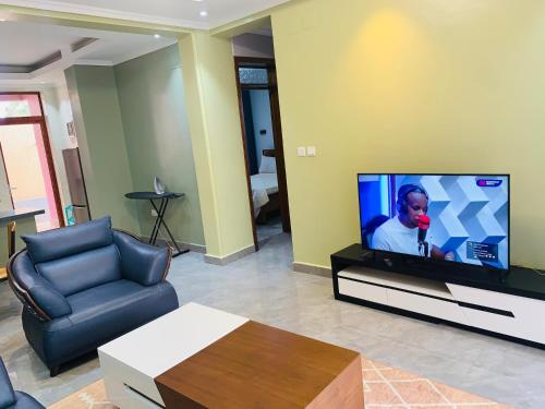 a living room with a flat screen tv and a couch at ROBERT Villa APARTMENT in Kigali